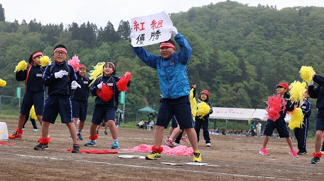 プラカードやポンポンを持って熱心に応援する紅組応援団の写真