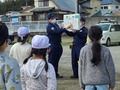 交通安全教室を行う2人の講師とその説明を立って聞く生徒たちの写真