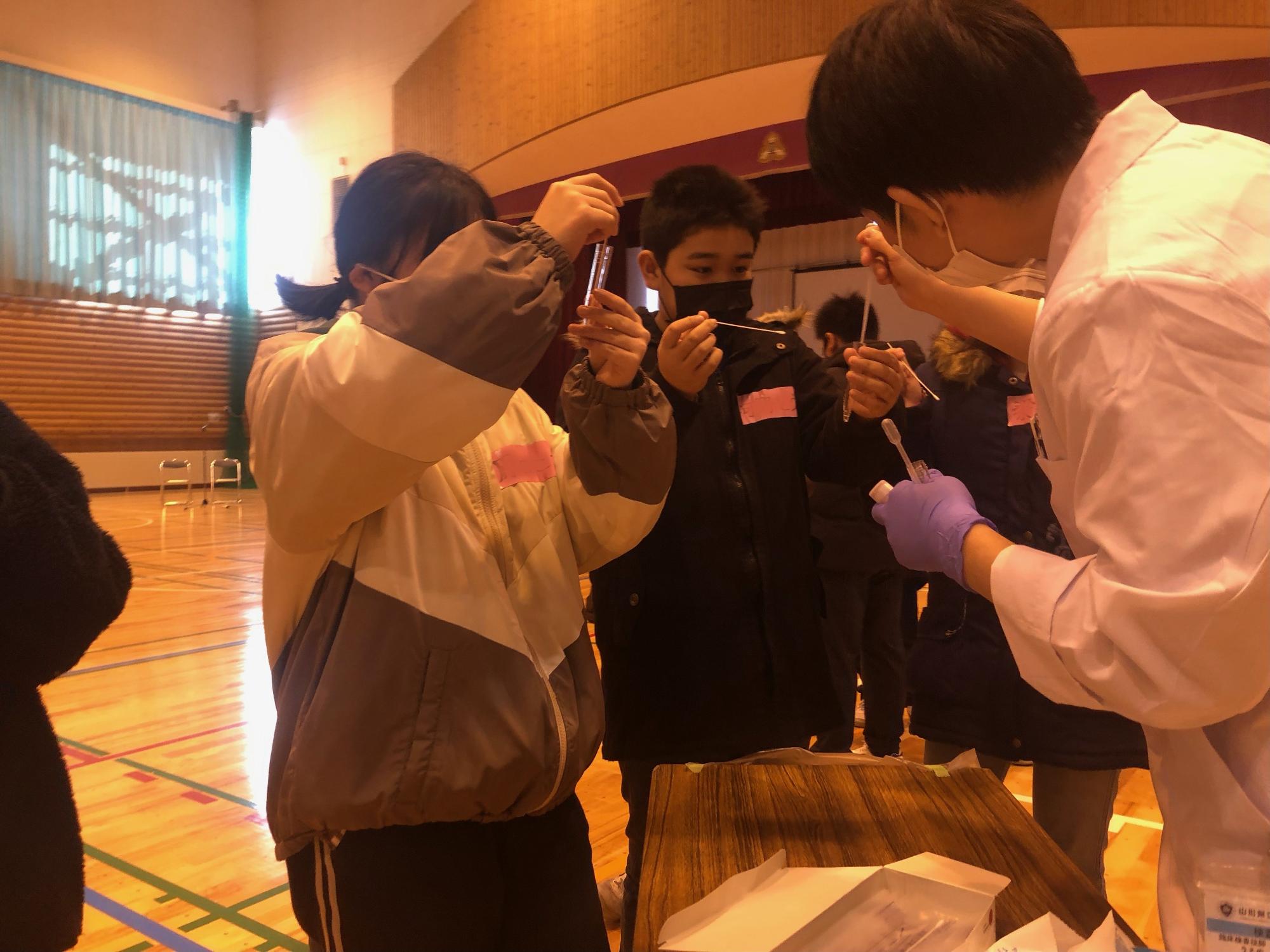 医療・介護の模擬体験として臨床検査の体験をしている生徒たちの写真