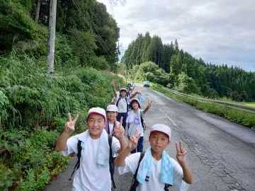 なだらかな山道を縦2列に並び楽しそうに歩く児童たちの写真