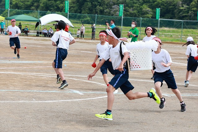 かごを背負い、走り回る男子児童の写真