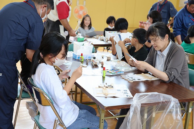夢中になって紙に細工をしてい女性と女子児童の写真