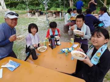 一緒に芋煮を楽しむ神室少年自然の家の職員の皆さんと児童たちの写真