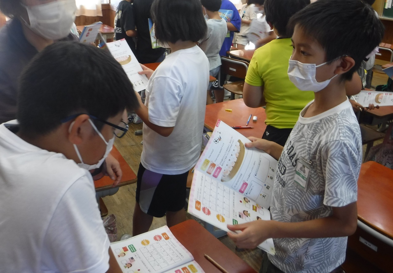 英語の教科書を手に持って向かい合っている男の子2人の写真