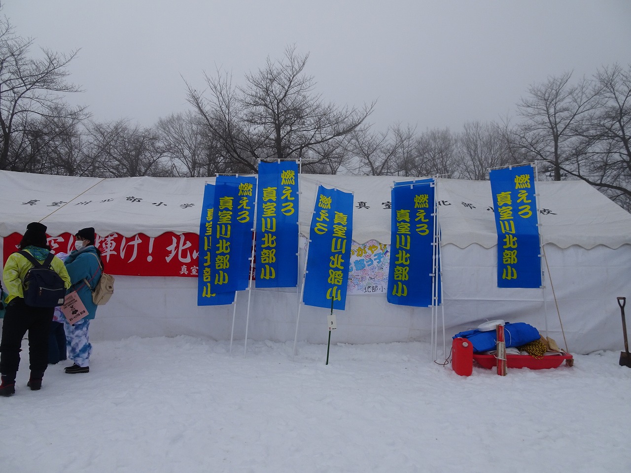 秋山スキー場で開催されたスキー大会にて、真室川北部小学校の待機場にいくつも掲げられた、「燃えろ真室川北部小」と書かれた縦長の青い応援旗を写した写真