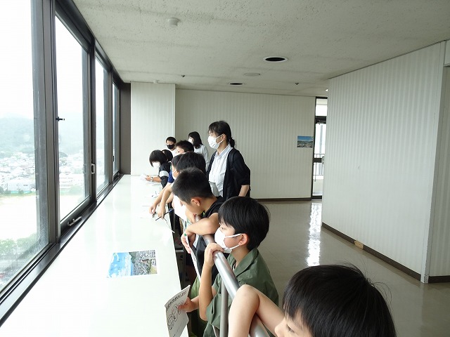 展望台の手すりに寄りかかり山形市の眺望を楽しむ児童たちの写真