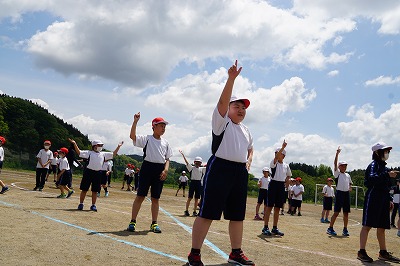 空を指さすようなポーズをとる児童たちの写真