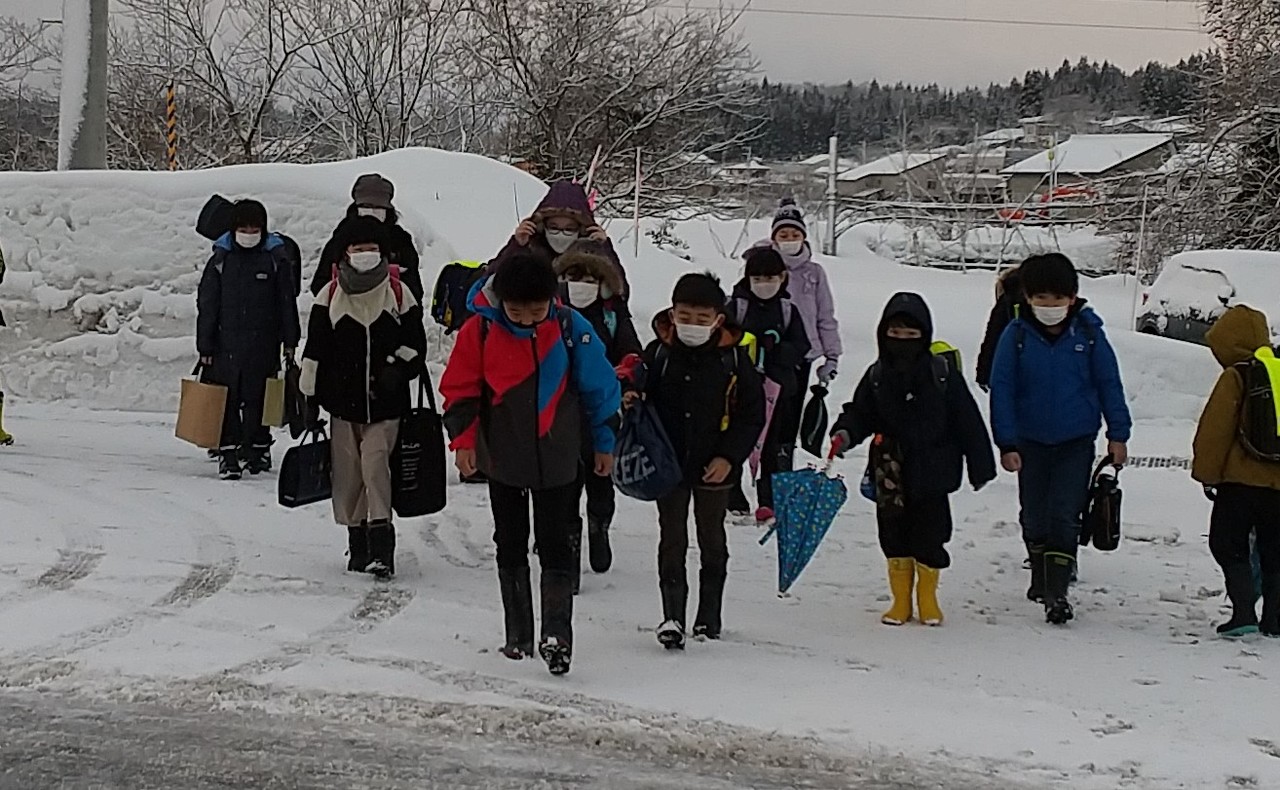 雪の積もった道を歩く子供たちの写真