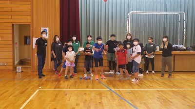 体育館の舞台の前で準備をする、PTA関係者と児童の写真