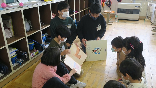5年生の4人の児童が、新入児童4人に、絵本の読み聞かせをしている様子の写真