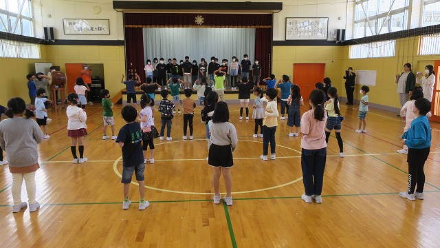 体育館で、町の陸上大会に参加する選手にエールを送る児童たちを、後ろから撮った写真