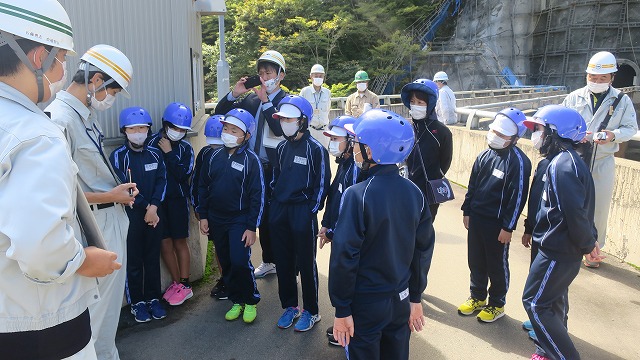 高坂ダムにて山形県最上総合支庁建設部高坂ダム管理課の話を聞く生徒たちの写真