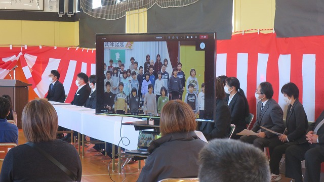 10周年記念式典・記念講演会を行う生徒たちと座って聞く先生と保護者たちの写真