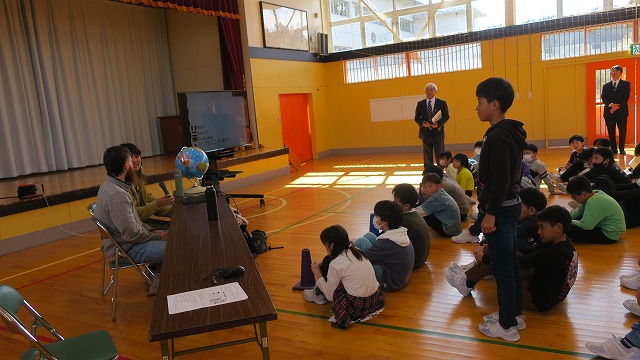 体育館で立ち上がって質問している児童と返答しようとしている地域おこし協力隊インターンの男女の写真