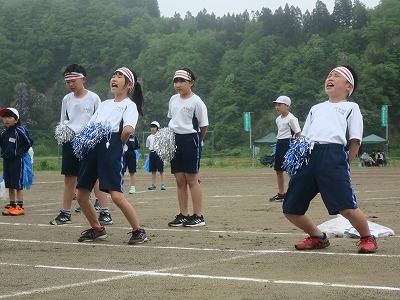 白いハチマキに青と白のポンポンを手に持って大声を張り上げて応援する白組児童たちの写真