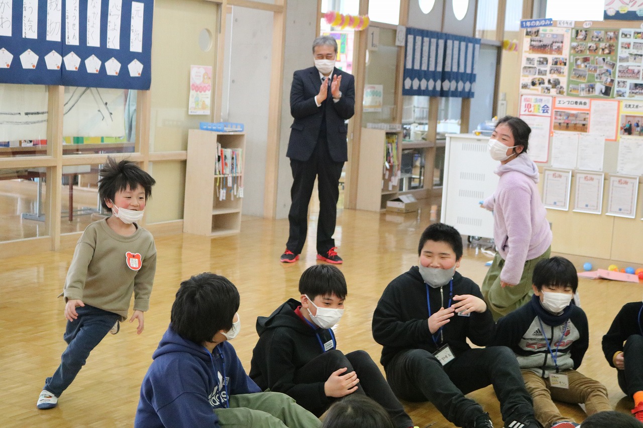小学校の教室内で行われた新入生体験入学にて、5年生と入学前の児童達が、床に座りなが遊んでいる様子を写した写真