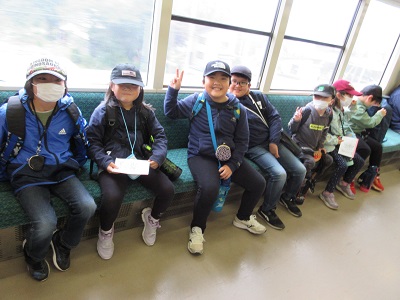 電車の座席に座って笑顔を見せる帽子を被った子供たちの写真