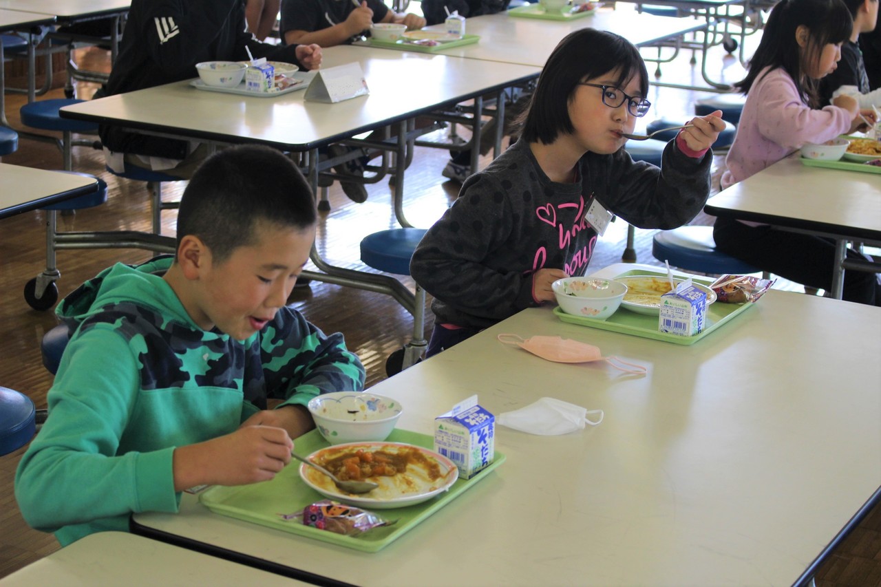横に並んでカレーを食べる子供たちの写真