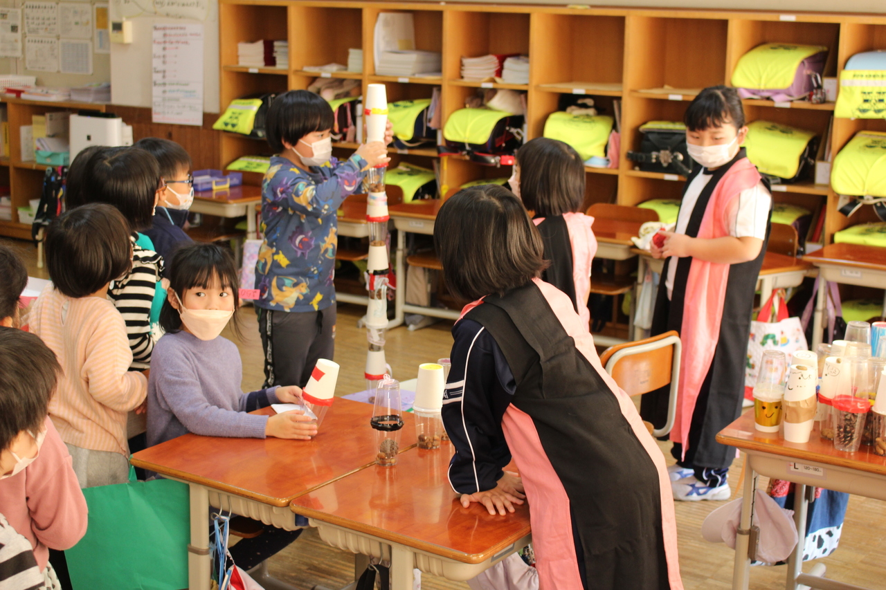 紙コップを何層にも重ねて塔を作っている子供の写真