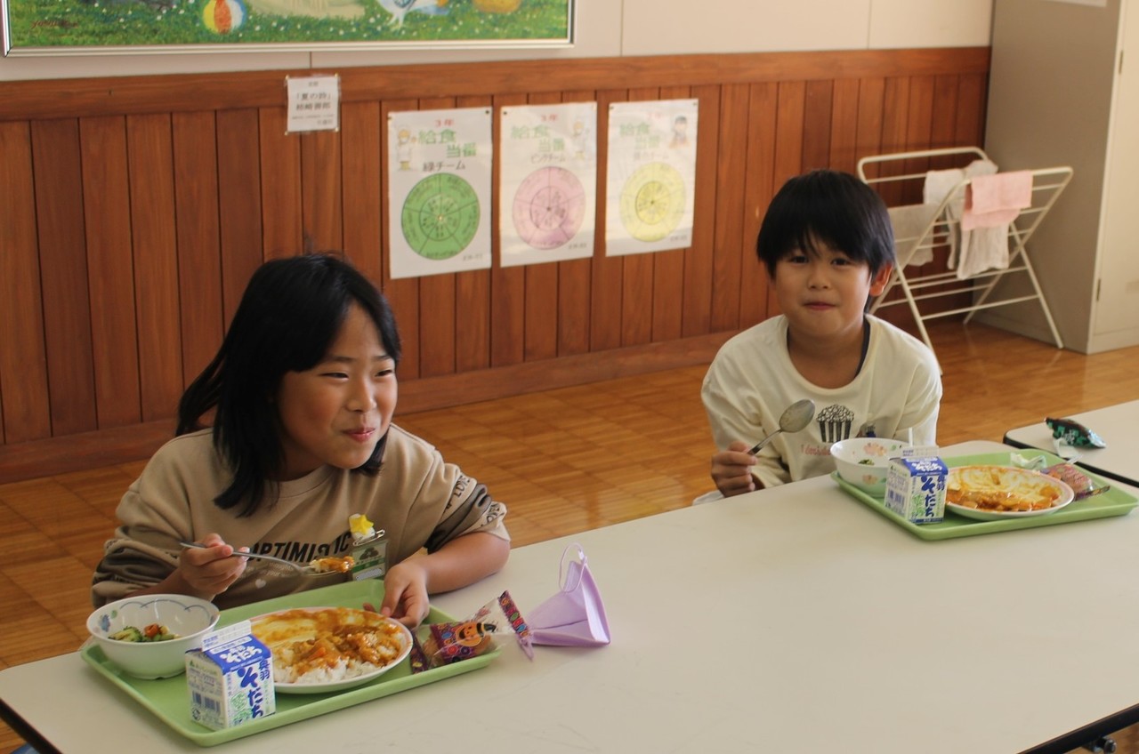 カレーを食べて微笑む二人の子供の写真
