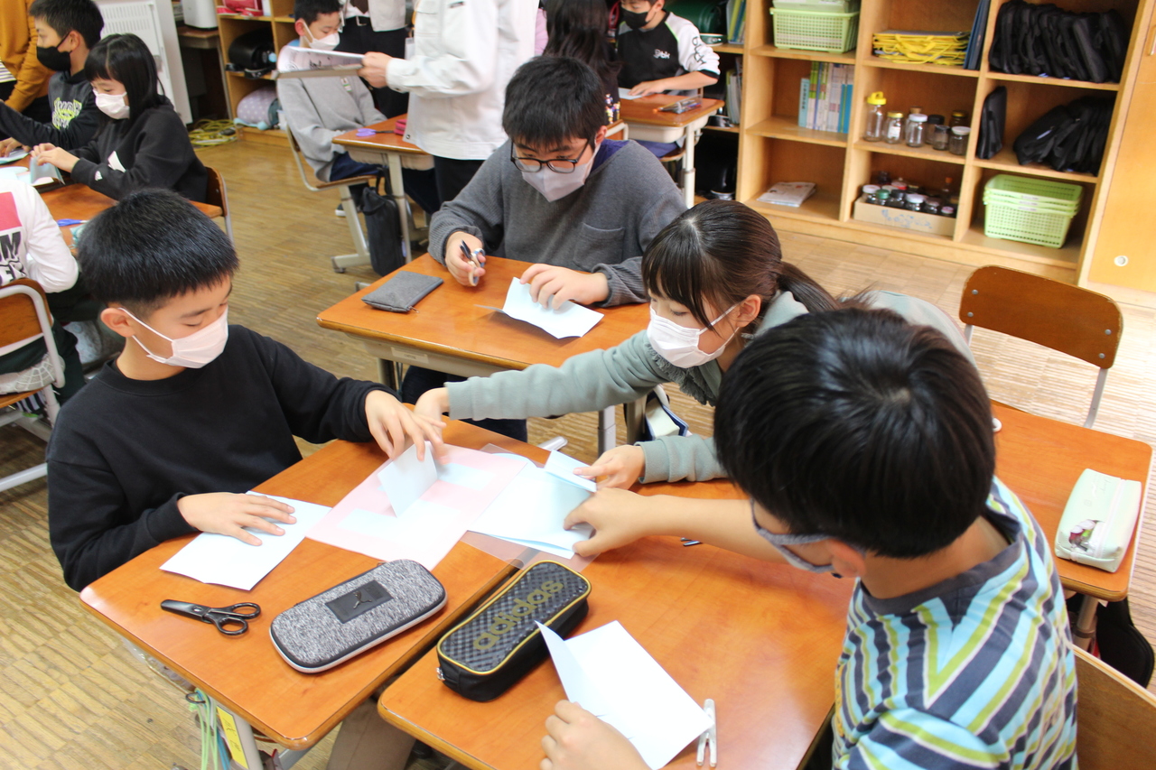 並べた机の上で紙をめくる子供たちの写真