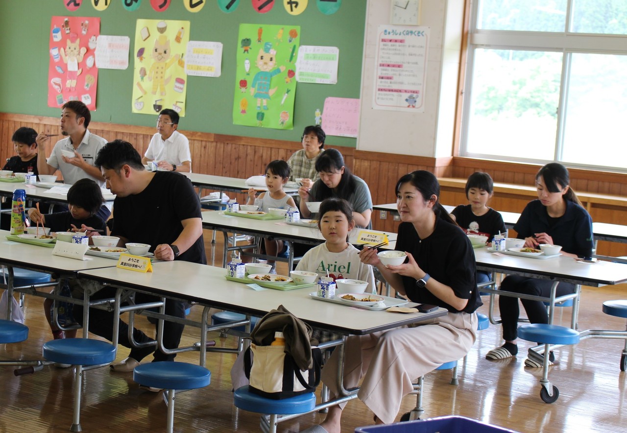 親子で並んで給食を食べている写真