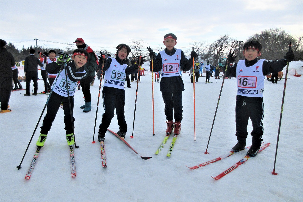秋山スキー場で開催されたスキー大会にて、スキーの装備を身につけた4人の男子児童が、各々ポーズを取りながら撮影された記念写真