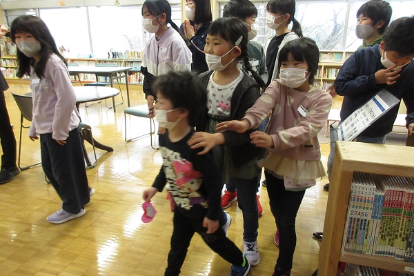 肩に手をつけながら一緒になって歩く子供たちの写真
