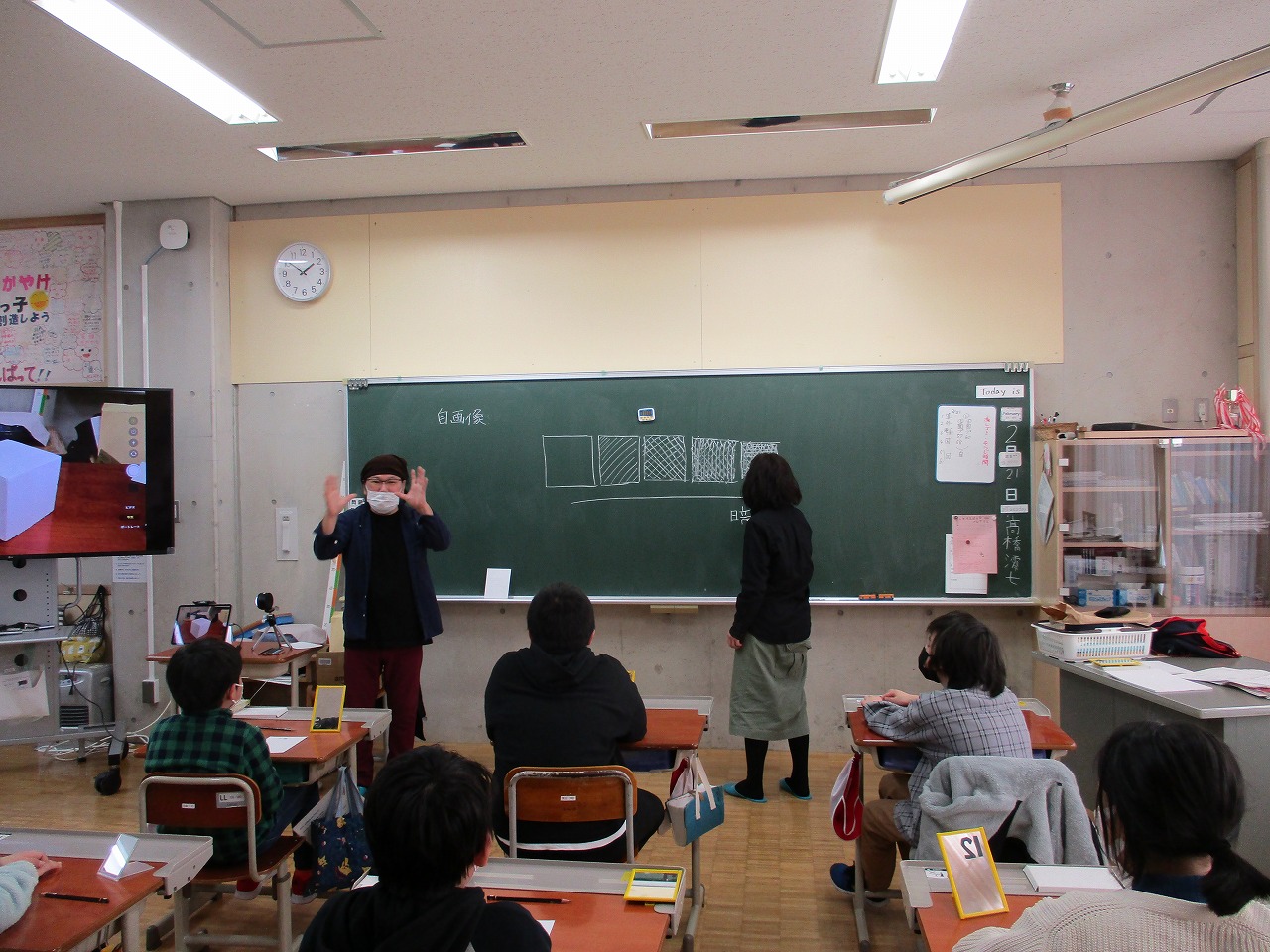 影の明るさの段階を説明する絵本作家あるほなつきさんと説明を座って聞く5・6年の児童たちの写真