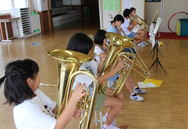 チューバやトロンボーンなどの金管楽器を演奏する子供たちの写真