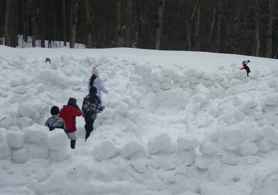 雪のブロックを積んで作った迷路を歩く児童たちの写真