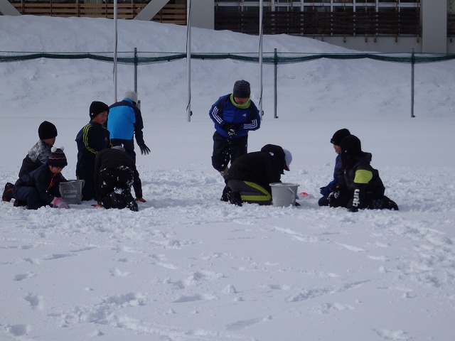 バケツに雪を集めている、8人の児童たちの写真