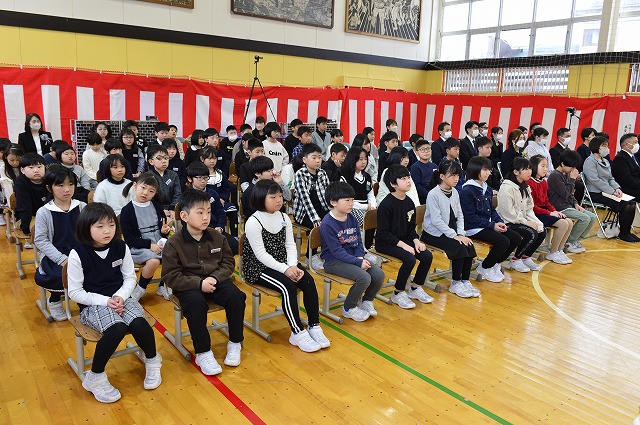 体育館の床に置かれた椅子に座って、卒業証書授与式を観ている在校生たちの写真
