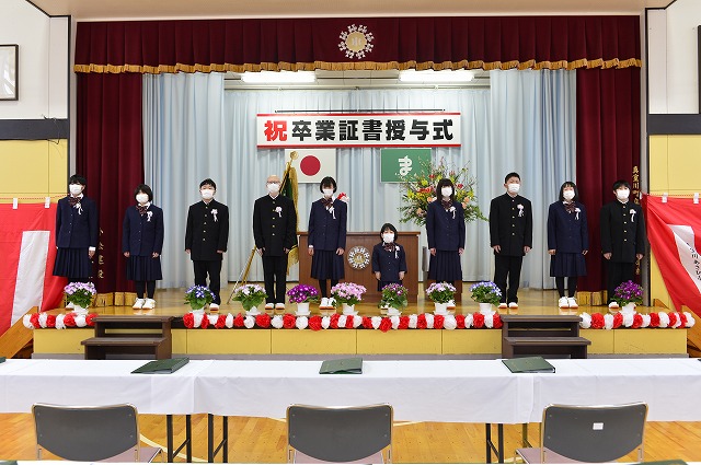 体育館の舞台に集合した制服姿の卒業生たちの写真