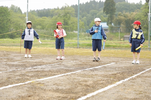 リレーのバトンを持ってスタートラインに立つ低学年女子児童たちの写真