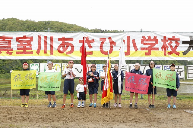紅組、白組の代表が、団旗を持ち互いに健闘をたたえ合う様子の写真