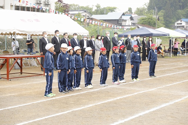 横一列に並び赤白に分かれて声を上げて応援する低学年児童たちの写真
