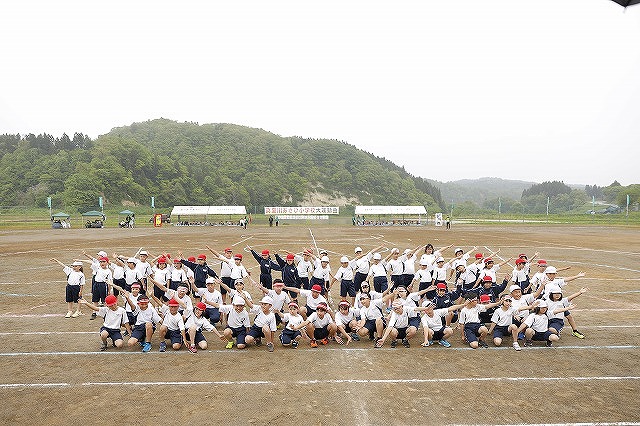 左右に腕を広げてパフォーマンスをする全校生徒の写真