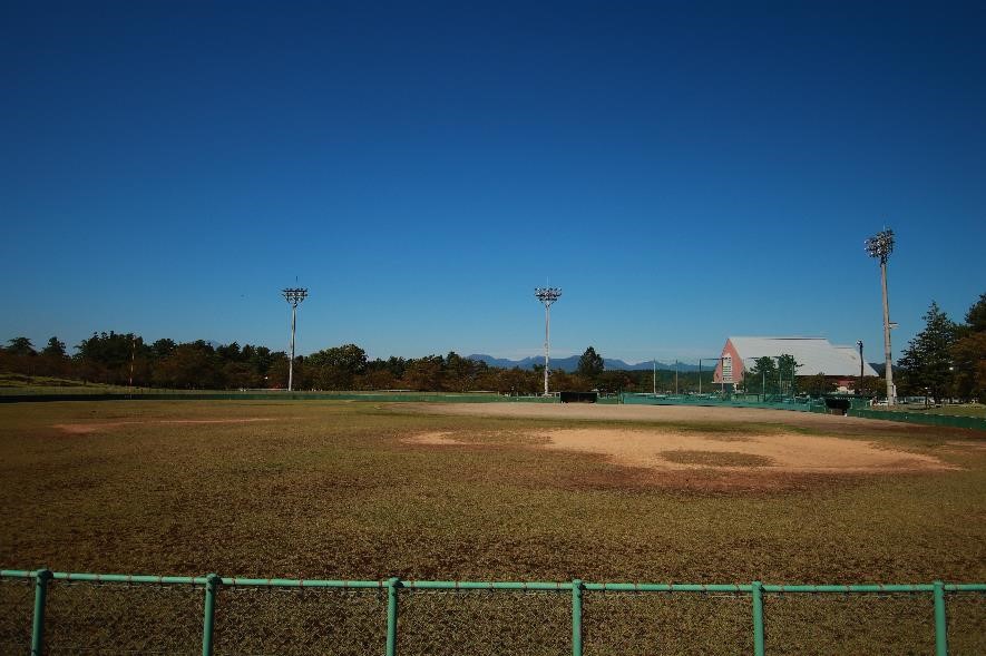向こうに体育館の見える広々とした野球場の写真