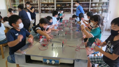 発電用の装置を相手に悪戦苦闘の中学年児童たちの写真