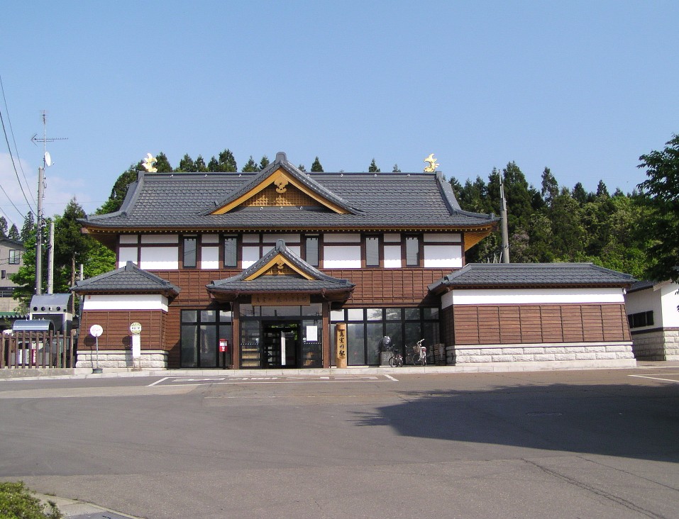 屋根は黒い瓦葺きで外壁は白と茶色の2色になっている、日本建築のような見た目の駅舎の外観を正面から撮影した写真