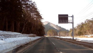 歩道側に雪が積もっている道路の写真