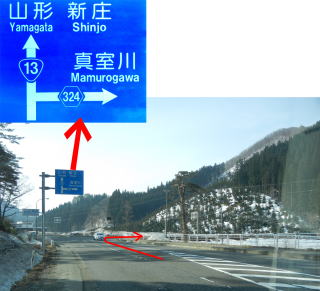 道路の奥に見えている、直進 山形・新庄方面と右折 真室川方面を示した標識を大きく表示している写真