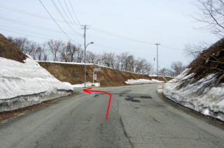 雪の積もる道路に左折するよう矢印が書き込まれている写真