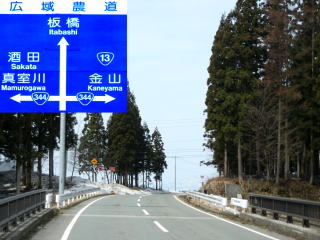 緩いカーブのかかった道路の写真、道路標識の拡大写真の二枚が並んでいる写真