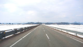 雪の積もった地面と道路が遠くまで続いている写真