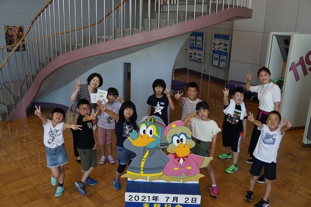 カルガモのマスコットの看板と生徒たちの来館記念写真