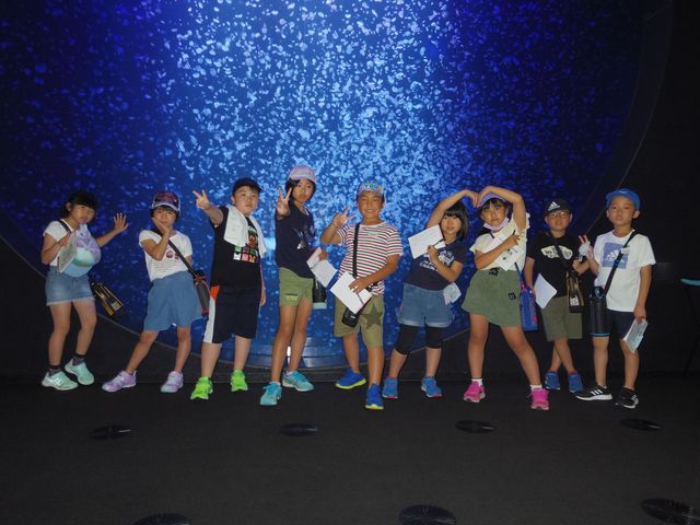加茂水族館の大きな水槽前で思い思いのポーズをとる生徒たちの記念写真