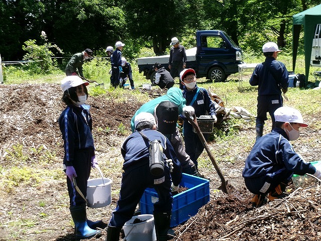 指導員の方とともに、木のチップをほぐす児童の写真