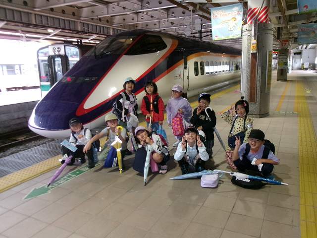 青い車体が印象的な新幹線の前で記念撮影をする児童たちの写真